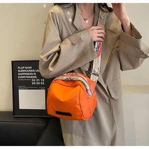 Fashionable orange nylon crossbody bag with colorful geometric strap shown on model