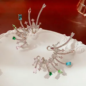 Silver drop wing ear cuffs with colorful gemstones and crystals on relief ceramic plate