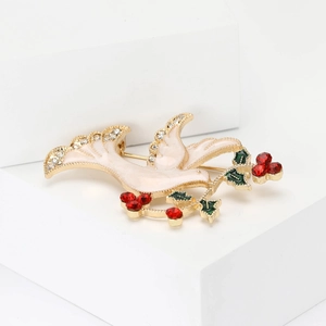 Enamel dove brooch with gold plating and red rhinestones on a white geometric stand