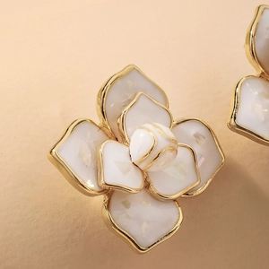 Macro shot of camellia flower stud earrings with pearlescent petals and golden edges