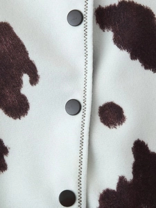 Detail of cow print plush fabric with three black buttons and zigzag stitching