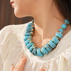 Gros plan d'un collier vintage avec perles bleues marbrées et espaceurs dorés