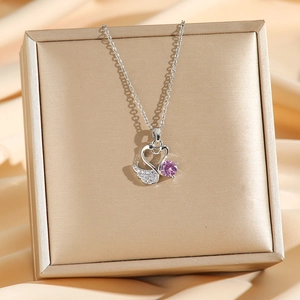Collier cygne en argent avec zircon rose sur boîte à bijoux dorée et tissu en soie