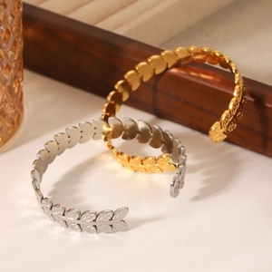 Detailed view of leaf shaped open cuff bracelets in polished gold and silver steel finish