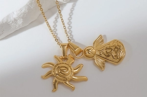 Close-up of golden sun and Hamsa hand pendants with detailed elephant relief on stone