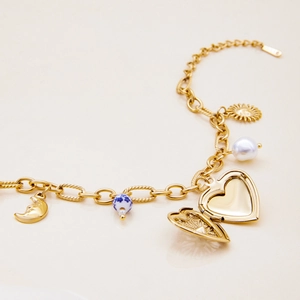 Detail of vintage gold layered bracelet with heart locket and celestial pendants