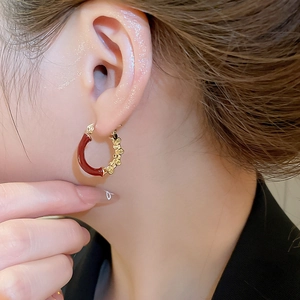 Gros plan de boucles d'oreilles créoles vintage en émail rouge et or texturé