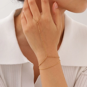 Elegant gold-tone stainless steel finger bracelet with tassel chain on a model's hand