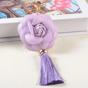 Detail view of purple PU leather flower keychain with golden hardware and tassel charm