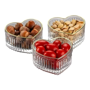 Drie hartvormige glazen schalen met gouden rand voor snacks en fruit op witte basis
