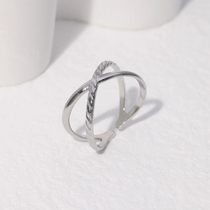 Macro detail of silver minimalist crossover open ring with polished metal finish