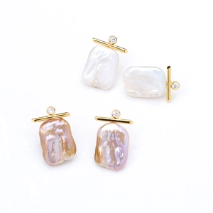 Close-up of baroque pearl earrings with gold-plated bars and sparkling cubic zirconia