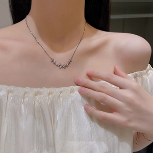 Dettaglio di una collana in acciaio al titanio argento con ciondolo a farfalla su una modella