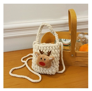 Close-up of knit reindeer crossbody bag with soft 3D doll on wooden tabletop