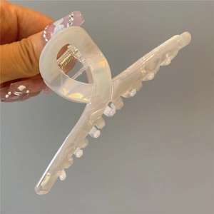 Close-up of elegant pearlescent white acetate hair claw clip with curved abstract design