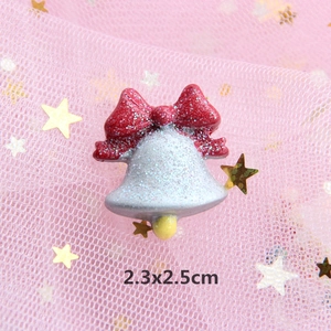 Detail of DIY Christmas resin bow with silver bell and glitter on pink mesh background