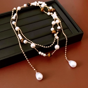 Detail of vintage layered necklace featuring pearls, tiger eye stones and gold accents