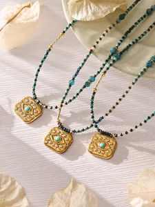 Detail of bohemian evil eye pendant necklaces with turquoise beads on textured ceramic