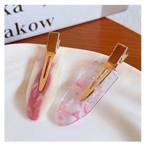 Close-up of two pink seamless hair clips with resin finish and golden metal fasteners