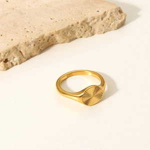 Détail d'une bague chevalière soleil plaquée or 18K sur un support en pierre