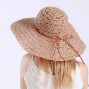 Detail of breathable hollow-out straw weaving and brown leather bow on summer sun hat