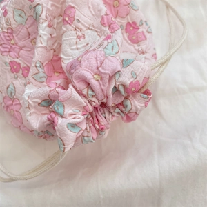 Close-up of pink floral drawstring storage bag with pleated fabric texture and cotton rope