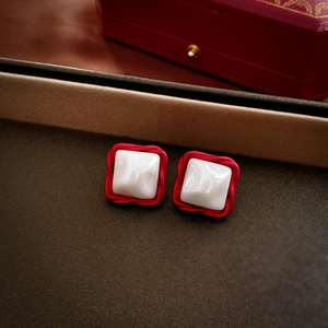 Macro view of French vintage square earrings with red textured frame and pearly white stone