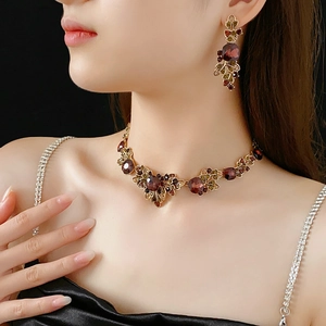 Detail of vintage necklace and earrings set with red floral gems on a model