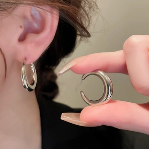 Close-up of silver geometric hoop earrings showing the polished finish and C-shape design