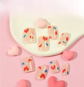 Close-up of nude press on nails with red, blue heart patterns and white dots