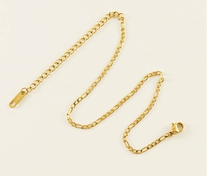 Makro-Detail des 18K Gold Figaro Fußkettchens mit S.STEEL Gravur auf weißem Hintergrund