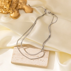 Detail view of silver layered snake chain and twisted rope necklace on a stone base