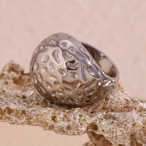 Détail macro de l'anneau argenté à texture martelée sur fond de corail naturel