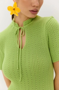 Dettaglio vestito in maglia verde brillante con colletto stringato e trama a costine