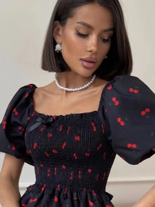 Detail of square neck dress with red cherry print, ribbon bow and smocked bodice texture