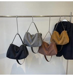 Row of suede tote bags in black grey brown and camel hanging from a metal rack