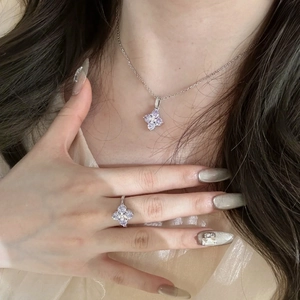 Detail shot of a silver four-leaf clover jewelry set with sparkling purple zircon stones