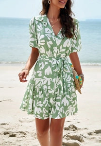 Detail of V-neck shirt dress with green leaf print, button closure and ruffles on beach