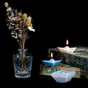 Makroaufnahme der Papierschiffchen-Silikonform und Duftkerzen auf alten Büchern