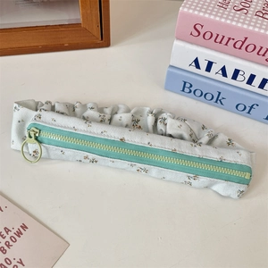 Detailed close-up of floral fabric pencil case with mint green zipper and large ring pull