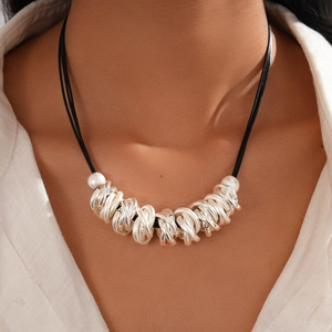Detailed close-up of layered black cord necklace with tangled silver geometric rings