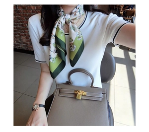 Detail of green floral silk scarf paired with a leather handbag and floral watch