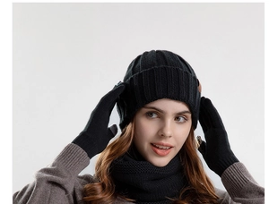 Detailed close-up of a three-piece black knitted winter set including hat, scarf, and gloves
