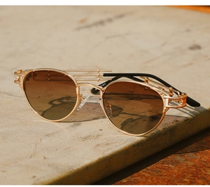 Detail of steampunk metal sunglasses with gold frames and brown gradient lenses on stone