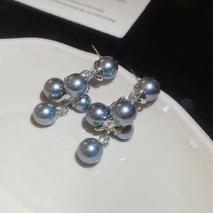 Detail of grey pearl drop earrings with silver pins on a white ceramic display tray