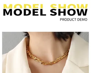 Close-up of a gold U-shaped gauge link necklace worn on a model with a white suit