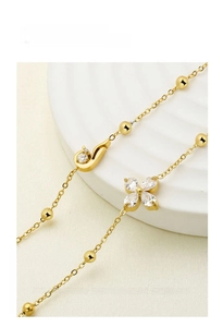 Macro shot of gold-plated bracelet featuring zircon four-leaf petals and polished beads