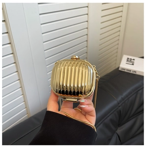 Close-up of gold mini acrylic clutch bag with vertical stripe texture and chain