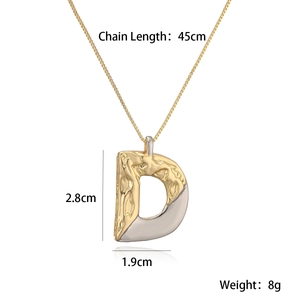 Detail of two-tone gold and silver letter D pendant with textured lava finish and measurements