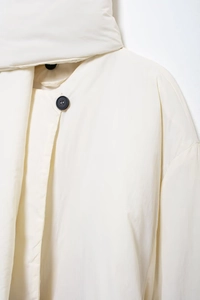 Nahaufnahme der cremeweißen Steppjacke mit Schalkragen und schwarzem Knopfverschluss